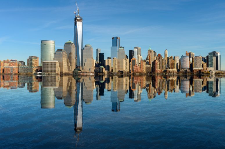 Lower Manhattan skyline panorama over East River with reflection and blue sky in New York City