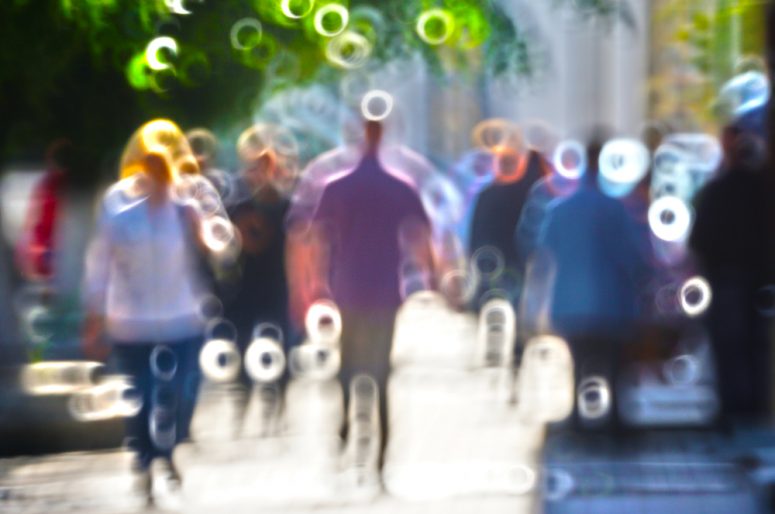 Blurred silhouettes of people walking on the street against backlight