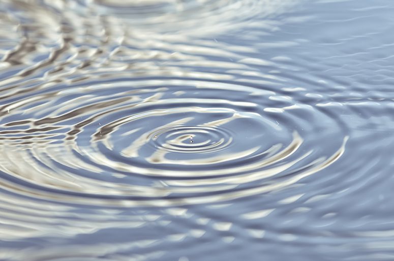 Round droplets of water over the circles on the water. Ripples on sea texture. Closeup water rings